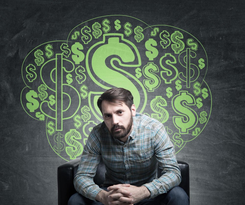 Bearded Product Owner Near Blackboard With Dollar Signs Drawn On It Symbolizing Its Salary Expectations